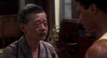 An older man with a mustache talking to a younger man