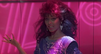 Movie still from “The Last Dragon” (1985), directed by Michael Schultz – A person with long hair wearing a dress; Close Up shot, Over the shoulder angle