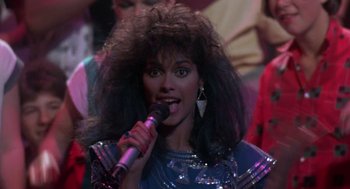 Movie still from “The Last Dragon” (1985), directed by Michael Schultz – A woman with a microphone in her hand; Close Up shot, Over the shoulder angle