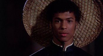 Movie still from “The Last Dragon” (1985), directed by Michael Schultz – A young man wearing an oriental costume and a straw hat; Close Up shot, Low angle