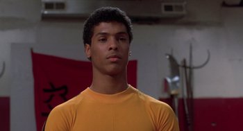 Movie still from “The Last Dragon” (1985), directed by Michael Schultz – A man in a yellow shirt is standing in a gym; Close Up shot, Low angle