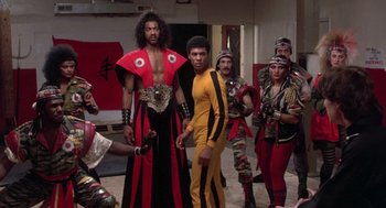 Movie still from “The Last Dragon” (1985), directed by Michael Schultz – A group of men in costumes standing next to each other in a room; Wide shot, Low angle