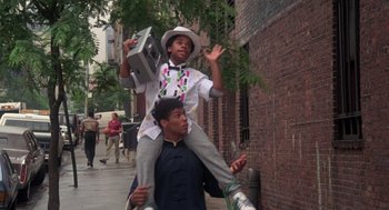 Movie still from “The Last Dragon” (1985), directed by Michael Schultz – A young man carrying a young man on his shoulders; Medium shot, Low angle