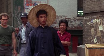 Movie still from “The Last Dragon” (1985), directed by Michael Schultz – A man wearing a straw hat while standing next to another man; Medium shot, Over the shoulder angle