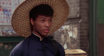 Movie still from “The Last Dragon” (1985), directed by Michael Schultz – A man wearing a straw hat and a blue jacket; Close Up shot, Over the shoulder angle