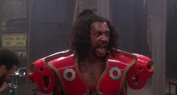 Movie still from “The Last Dragon” (1985), directed by Michael Schultz – A man in a red and gold costume with a long black beard; Close Up shot, Low angle