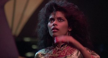 Movie still from “The Last Dragon” (1985), directed by Michael Schultz – A woman with long black curly hair is holding a cell phone; Close Up shot, Low angle
