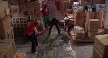 Movie still from “The Last Dragon” (1985), directed by Michael Schultz – A group of young people playing a game of hopscotch in a warehouse; Wide shot, High angle