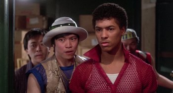 Movie still from “The Last Dragon” (1985), directed by Michael Schultz – Two young men standing next to each other in a crowd; Medium shot, Low angle