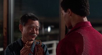 Movie still from “The Last Dragon” (1985), directed by Michael Schultz – A man is holding a piece of wood while another man looks at him; Close Up shot, Over the shoulder angle