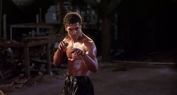 Movie still from “The Last Dragon” (1985), directed by Michael Schultz – A man in black shorts and a white shirt is boxing; Medium shot, Low angle
