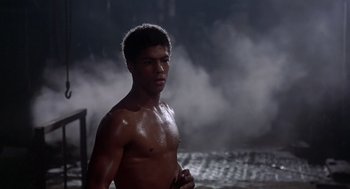 Movie still from “The Last Dragon” (1985), directed by Michael Schultz – A shirtless man standing in front of a body of water; Medium shot, Low angle