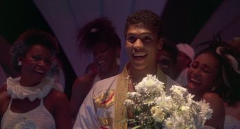 Movie still from “The Last Dragon” (1985), directed by Michael Schultz – A young man holding a bouquet of flowers in front of a crowd; Medium shot, Low angle