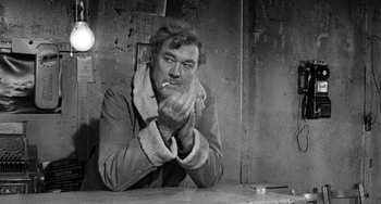 Movie still from “The Last Picture Show” (1971), directed by Peter Bogdanovich – A man sitting at a table smoking a cigarette; Close Up shot, Over the shoulder angle