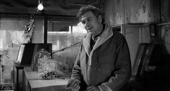 Movie still from “The Last Picture Show” (1971), directed by Peter Bogdanovich – A man in a jacket is standing in a room; Medium shot, Over the shoulder angle