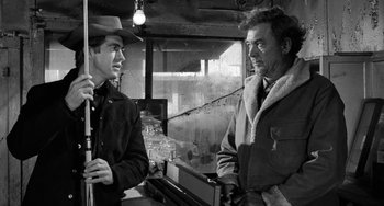 Movie still from “The Last Picture Show” (1971), directed by Peter Bogdanovich – A man and a man standing next to each other in a room; Medium shot, Over the shoulder angle