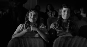 Movie still from “The Last Picture Show” (1971), directed by Peter Bogdanovich – Two young women sitting in a theater with their arms crossed; Medium shot, Low angle