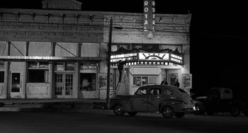 Movie still from “The Last Picture Show” (1971), directed by Peter Bogdanovich – An old car is parked in front of a theater at night; Extreme Wide shot, Low angle
