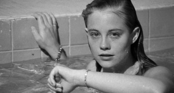 Movie still from “The Last Picture Show” (1971), directed by Peter Bogdanovich – A young woman sitting in a bath tub with a rosary; Close Up shot, Over the shoulder angle