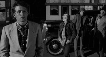 Movie still from “The Last Picture Show” (1971), directed by Peter Bogdanovich – A group of people standing next to a car; Medium shot, Low angle