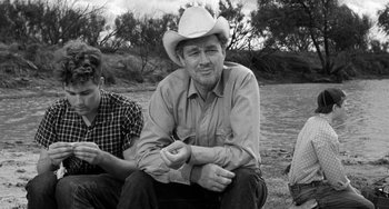 Movie still from “The Last Picture Show” (1971), directed by Peter Bogdanovich – A man sitting on the ground wearing a cowboy hat; Medium shot, Over the shoulder angle