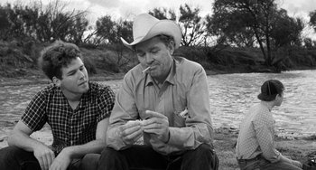 Movie still from “The Last Picture Show” (1971), directed by Peter Bogdanovich – A man wearing a cowboy hat is smoking a cigarette; Medium shot, Over the shoulder angle