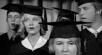 Movie still from “The Last Picture Show” (1971), directed by Peter Bogdanovich – Two women in graduation gowns and caps looking up at the sky; Close Up shot, High angle