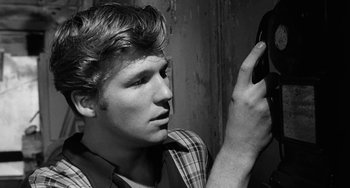 Movie still from “The Last Picture Show” (1971), directed by Peter Bogdanovich – A young man looking at his cell phone in black and white; Close Up shot, Over the shoulder angle