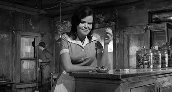 Movie still from “The Last Picture Show” (1971), directed by Peter Bogdanovich – A black and white photo of a woman holding a plate; Medium shot, Low angle