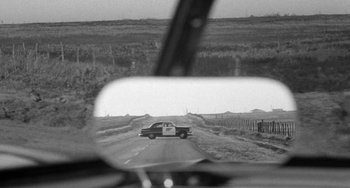 Movie still from “The Last Picture Show” (1971), directed by Peter Bogdanovich – A black and white photo of a car on the side of the road; Wide shot, Over the shoulder angle