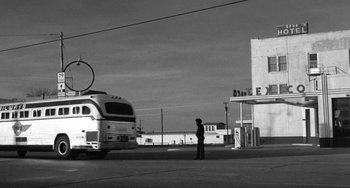 Movie still from “The Last Picture Show” (1971), directed by Peter Bogdanovich – A black and white photo of a man standing in front of a bus; Extreme Wide shot, Low angle