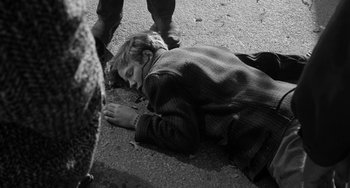 Movie still from “The Last Picture Show” (1971), directed by Peter Bogdanovich – A young child laying on the ground in the middle of the street; Close Up shot, High angle