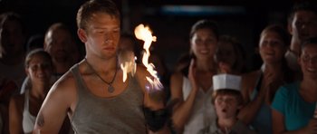 Movie still from “The Last Song” (2010), directed by Julie Anne Robinson – A young man is holding a fire stick in front of a group of people; Medium shot, Over the shoulder angle