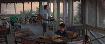 Movie still from “The Last Song” (2010), directed by Julie Anne Robinson – A man standing at a table with a plate of food; Wide shot, Over the shoulder angle