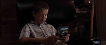 Movie still from “The Last Song” (2010), directed by Julie Anne Robinson – A young boy sitting in a chair looking at an electronic device; Close Up shot, High angle