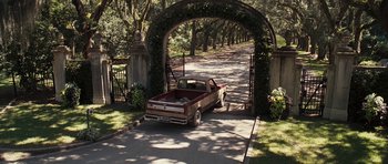 An old red pick - up truck parked under an archway