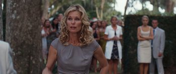Movie still from “The Last Song” (2010), directed by Julie Anne Robinson – A woman in a gray dress is standing in front of a group of people; Close Up shot, Over the shoulder angle