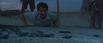 A young boy crawling on the ground at night