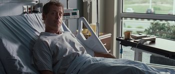 Movie still from “The Last Song” (2010), directed by Julie Anne Robinson – A man laying in a hospital bed holding a monitor; Medium shot, High angle