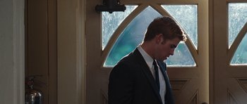Movie still from “The Last Song” (2010), directed by Julie Anne Robinson – A man in a suit and tie standing in front of a window; Medium shot, Low angle