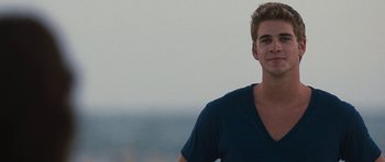 Movie still from “The Last Song” (2010), directed by Julie Anne Robinson – A young man in a blue t - shirt is smiling; Close Up shot, Over the shoulder angle