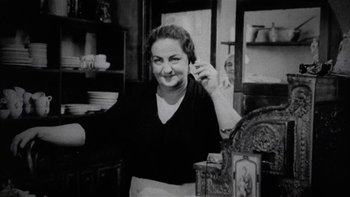 Movie still from “The Last Tycoon” (1976), directed by Elia Kazan – An old photo of an older woman in a kitchen; Medium shot, Low angle