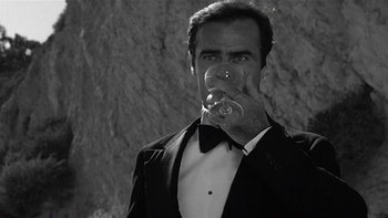 Movie still from “The Last Tycoon” (1976), directed by Elia Kazan – A black and white photo of a man in a tuxedo holding a glass of wine; Close Up shot, Low angle