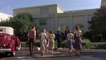 Movie still from “The Last Tycoon” (1976), directed by Elia Kazan – A group of people walking in front of a building; Wide shot, Low angle