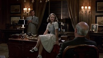 Movie still from “The Last Tycoon” (1976), directed by Elia Kazan – A woman sitting in front of a mirror in front of two men; Medium shot, Over the shoulder angle