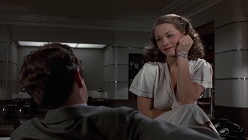 Movie still from “The Last Tycoon” (1976), directed by Elia Kazan – A woman sitting next to a man in a room; Medium shot, Over the shoulder angle