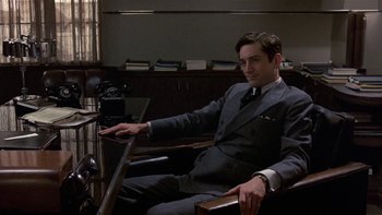 Movie still from “The Last Tycoon” (1976), directed by Elia Kazan – A man sitting in a chair in a suit and tie; Medium shot, Low angle