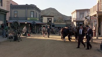 Movie still from “The Last Tycoon” (1976), directed by Elia Kazan – A group of people standing on a dirt road near buildings; Extreme Wide shot, High angle
