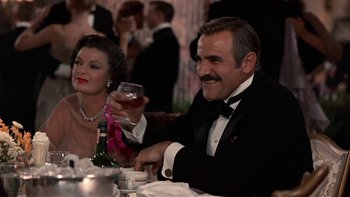 Movie still from “The Last Tycoon” (1976), directed by Elia Kazan – An older man sitting at a dinner table with a woman; Medium shot, Over the shoulder angle