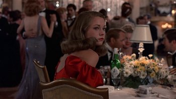 Movie still from “The Last Tycoon” (1976), directed by Elia Kazan – A woman sitting at a table in front of a crowd of onlookers; Medium shot, Over the shoulder angle